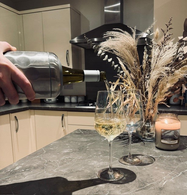 Silver wine cooler pouring a bottle of wine into 2 glasses